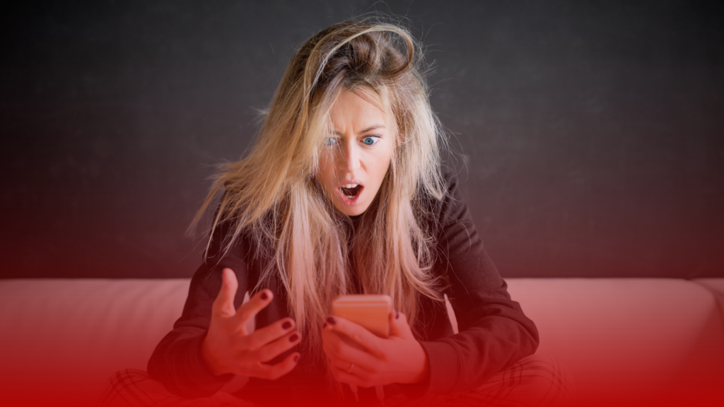 Uma mulher observando atentamente a tela de um celular, em um ambiente iluminado por tons de vermelho profundo. Sua expressão transmite sentimentos de reflexão e incerteza, representando um momento emocional delicado, pois ela descobriu que foi traída.