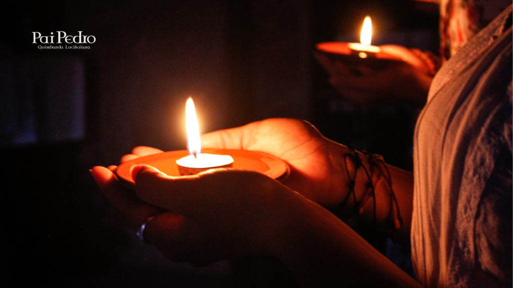 Em um ambiente escuro e silencioso, mãos humanas seguram delicadamente pequenos recipientes de barro com velas acesas. A chama brilha intensamente, iluminando suavemente os dedos e criando um clima de fé, introspecção e espiritualidade. Ao fundo, outras pessoas também seguram velas, sugerindo um ritual coletivo para Zé Pilintra. No canto superior esquerdo, está a marca “Pai Pedro — Quimbanda Luciferiana”.