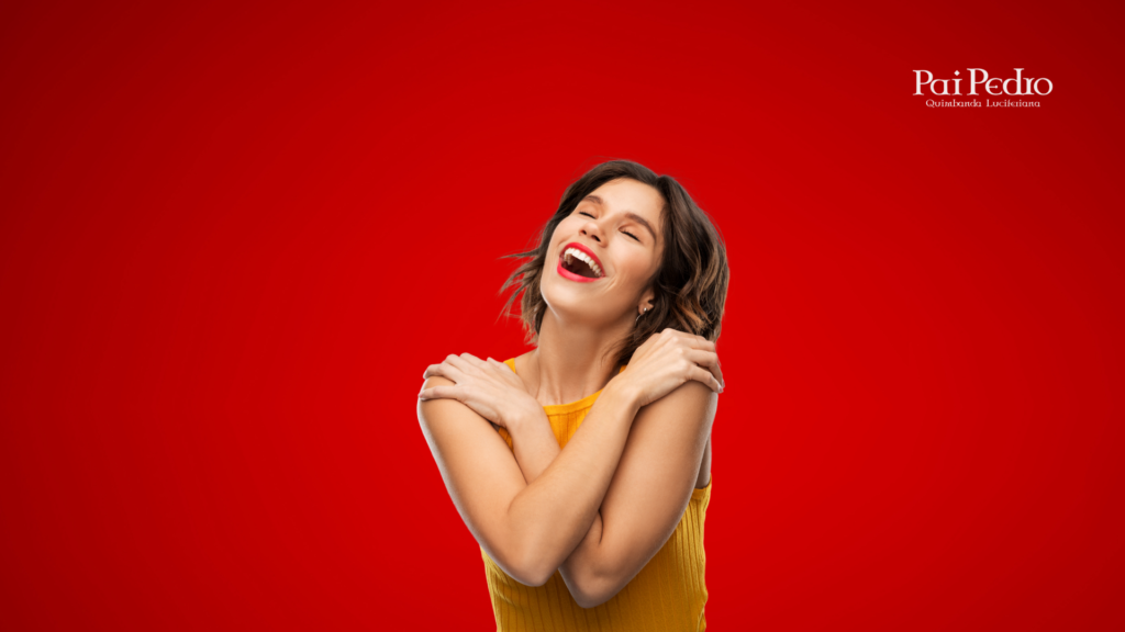 Mulher sorrindo com expressão de felicidade e autoestima, abraçando a si mesma em sinal de amor-próprio e superação emocional. Fundo vermelho transmitindo força e energia positiva.