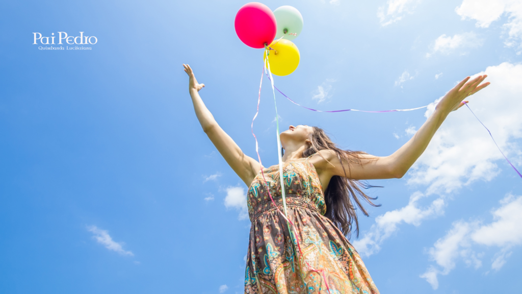 Mulher de braços erguidos sob o céu azul, soltando balões coloridos, simbolizando libertação emocional, autoconfiança e renovação após o fim de uma relação desgastada.