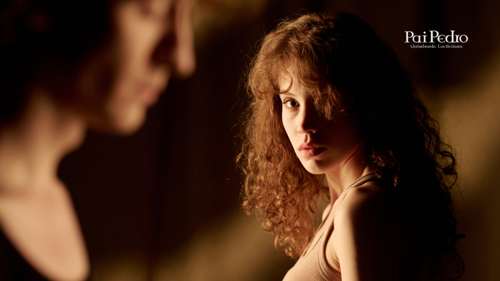 Mulher observando outra de forma atenta e desconfiada em ambiente de luz baixa, simbolizando sinais silenciosos de amiga falsa, inveja disfarçada e falsidade emocional.