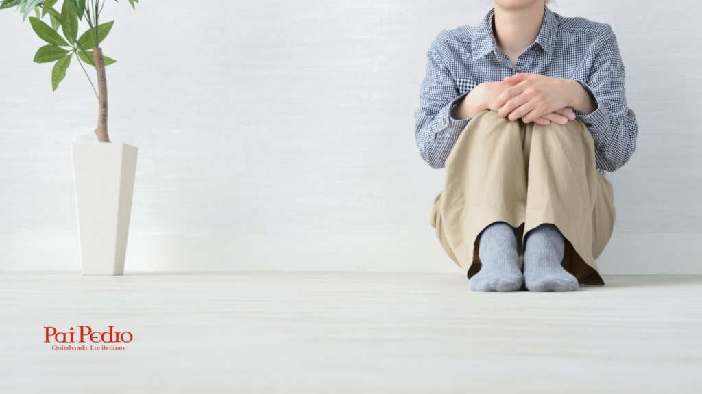 Mulher sentada no chão, abraçando os joelhos em um ambiente minimalista, simbolizando preocupação excessiva, ansiedade silenciosa e isolamento emocional causados pelo acúmulo de pensamentos.
