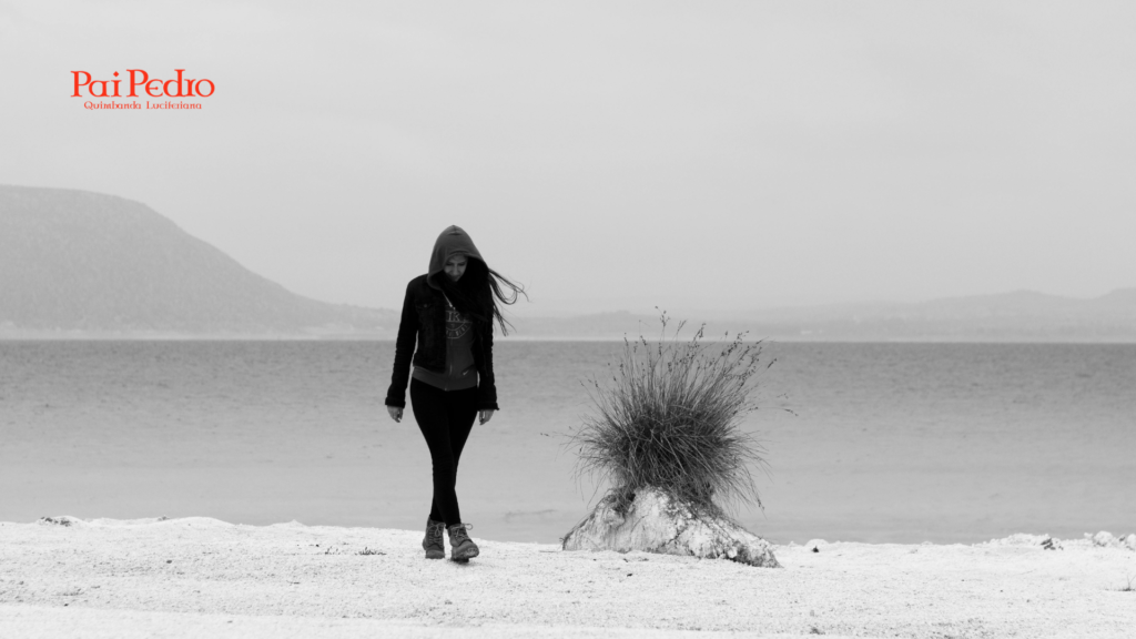 Mulher caminhando sozinha em paisagem deserta à beira-mar, simbolizando falta de amor no relacionamento e vazio emocional.