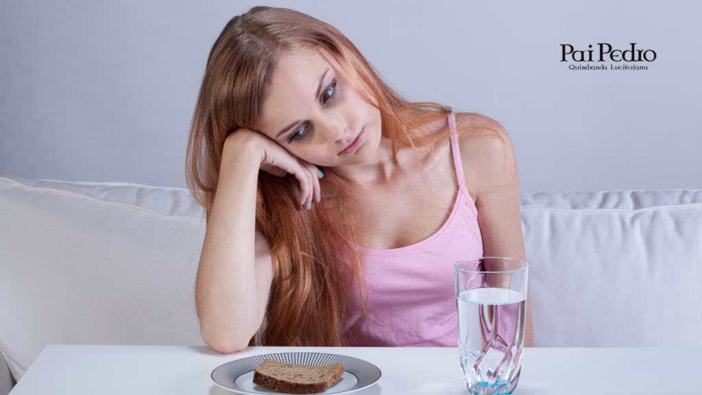 Mulher olhando para um prato simples com pão e um copo de água, demonstrando conflito emocional ligado ao comportamento alimentar e à restrição alimentar.