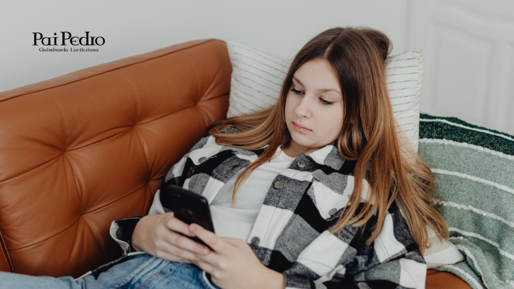 Jovem olhando o celular no sofá enquanto reflete sobre a comparação constante com outras mulheres nas redes sociais.
