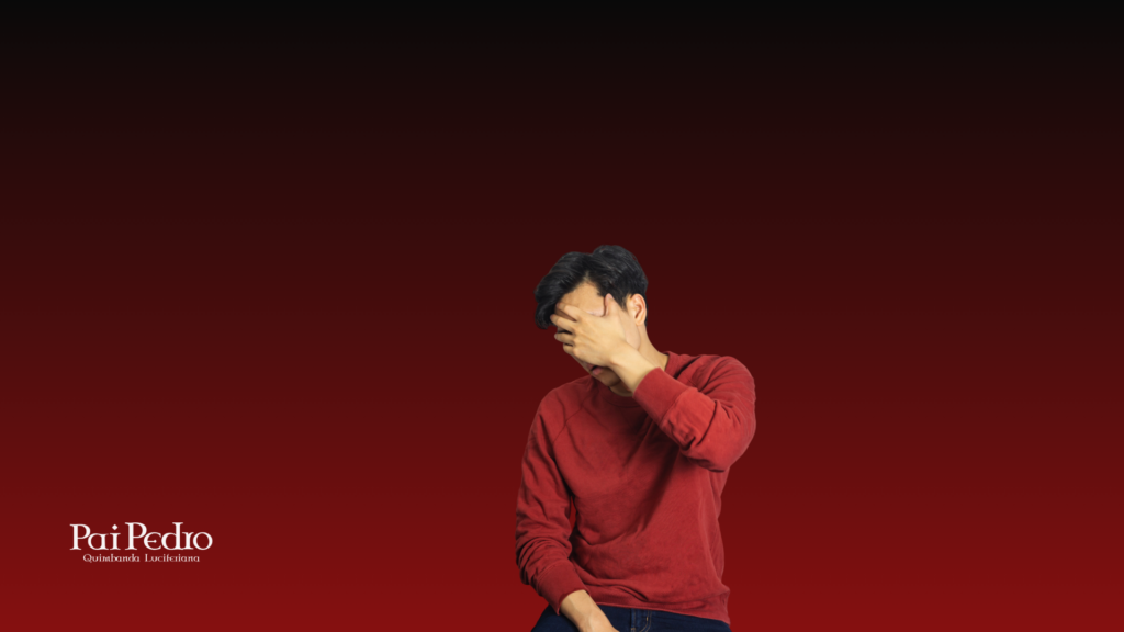 Homem tímido cobrindo o rosto com a mão em fundo vermelho, representando insegurança emocional e dificuldade de se expressar