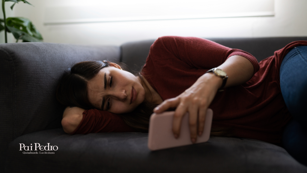 Mulher deitada no sofá olhando para o celular com expressão triste e abatida, representando a dor e a dúvida de quem pensa “ele me bloqueou”.
