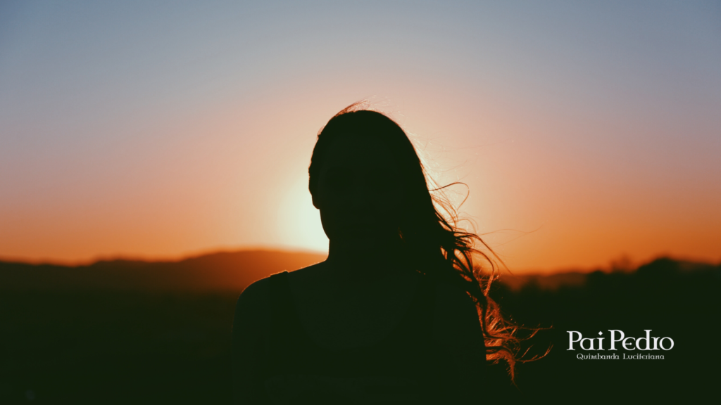 Silhueta de uma mulher observando o pôr do sol, transmitindo a sensação de distância emocional e reflexão. A imagem representa como a Gentileza Fria pode machucar ao substituir o afeto por uma cordialidade vazia, deixando apenas silêncio e afastamento.