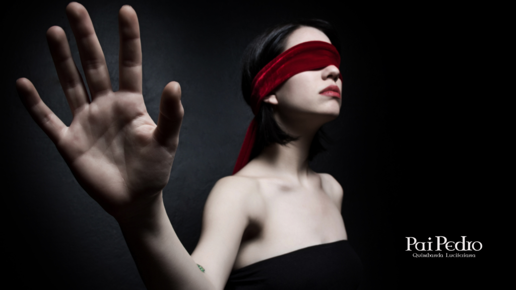 Mulher com os olhos vendados estende a mão no escuro, representando como romantizar no amor pode impedir que ela enxergue a relação como realmente é.